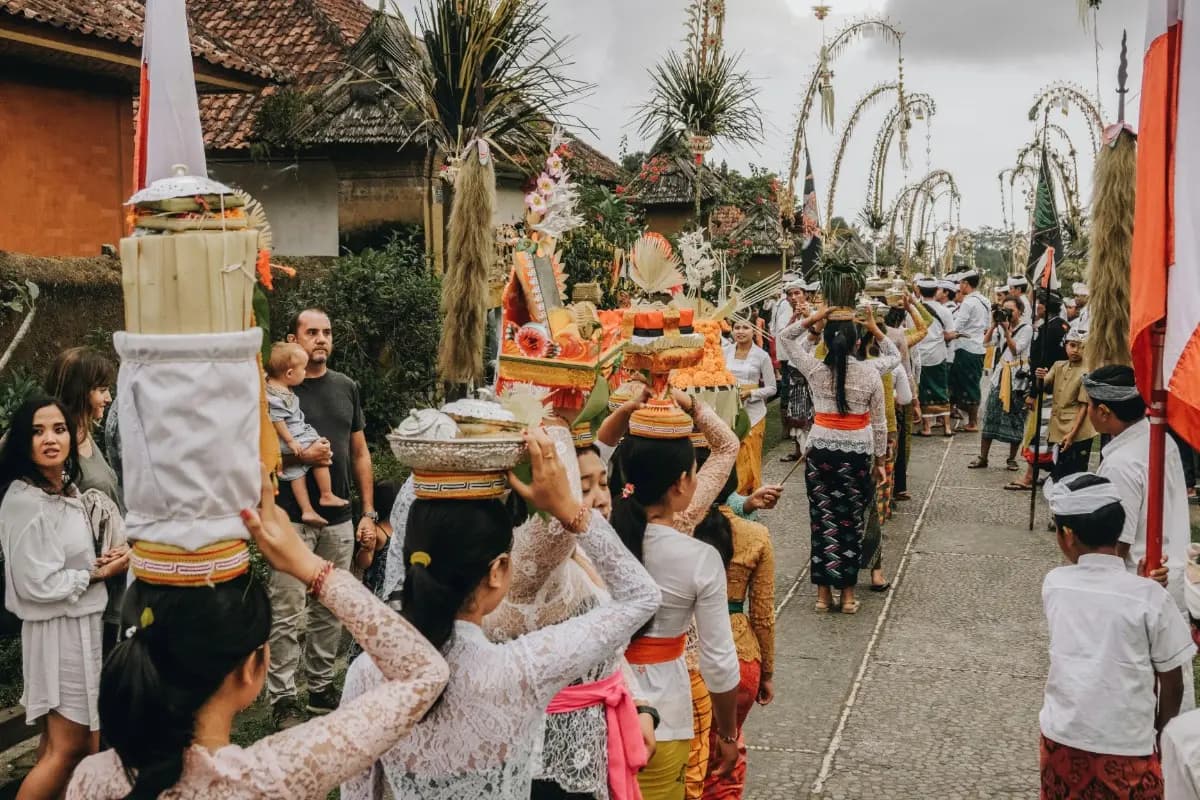 Balinese cultural procession with local residents carrying offerings during a traditional village ceremony.