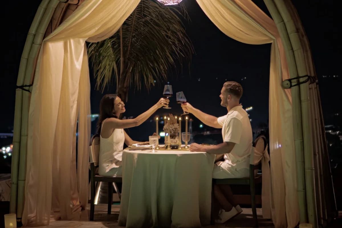 A couple shares a candlelit dinner and wine in a private cabana for a romantic evening in Bali.