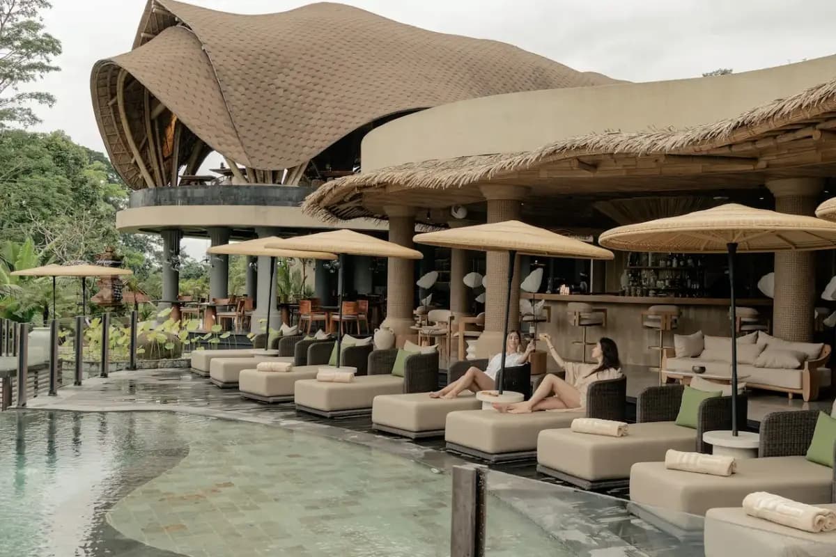 Guests relax beside an Ubud pool bar with cocktails, comfortable loungers, and peaceful jungle surroundings.
