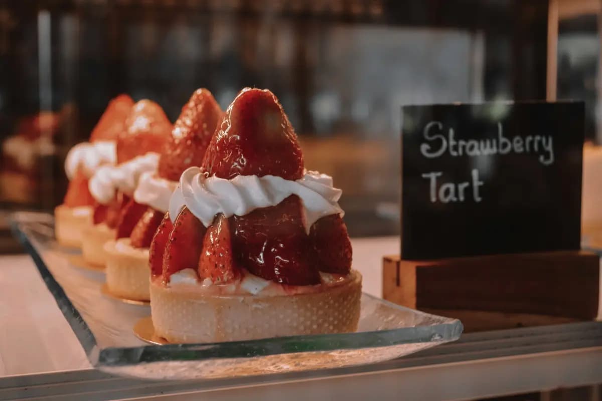 Fresh strawberry tarts topped with whipped cream are displayed for sale, highlighting Bali’s dessert options.