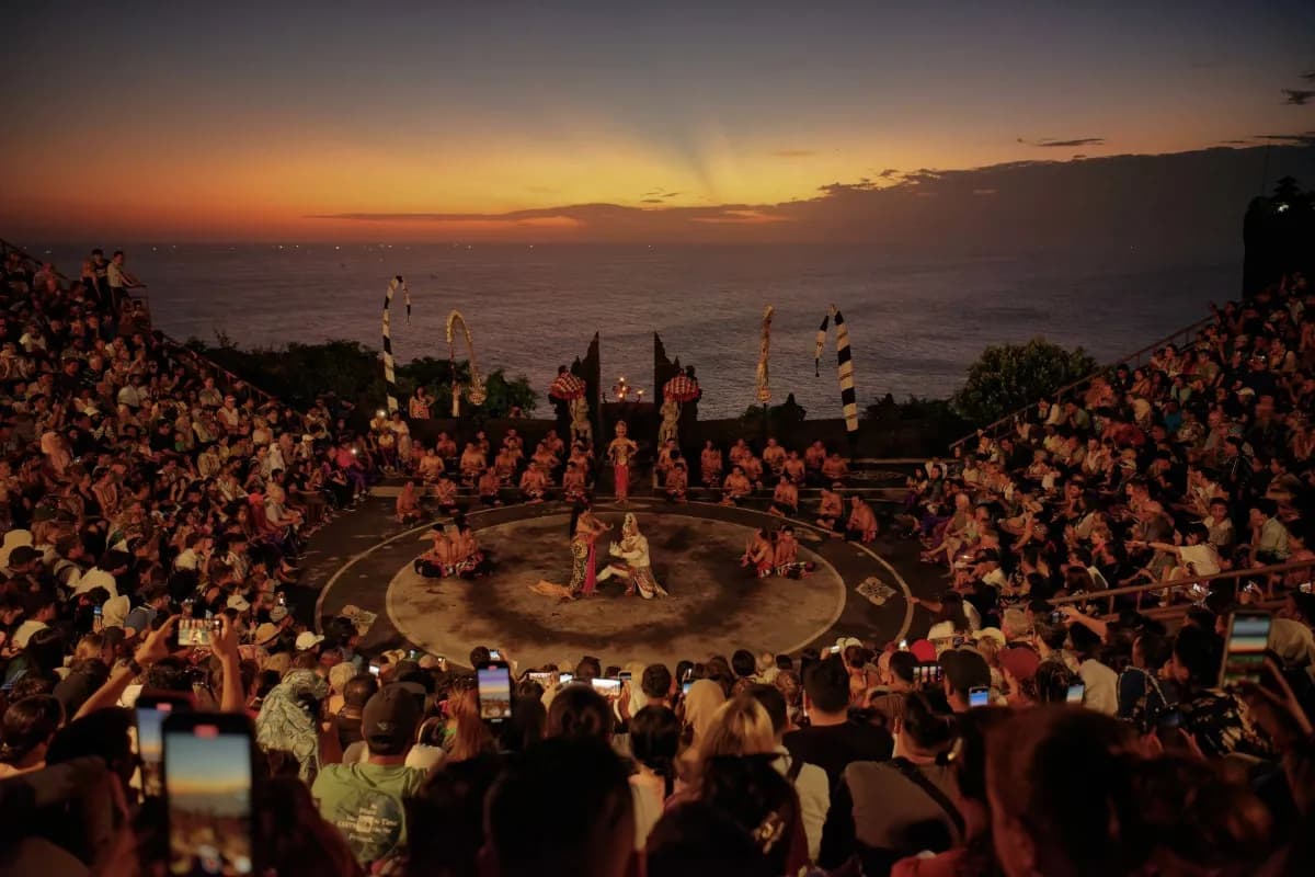 A large crowd watches the Kecak Fire Dance at Uluwatu Temple during sunset overlooking the ocean.