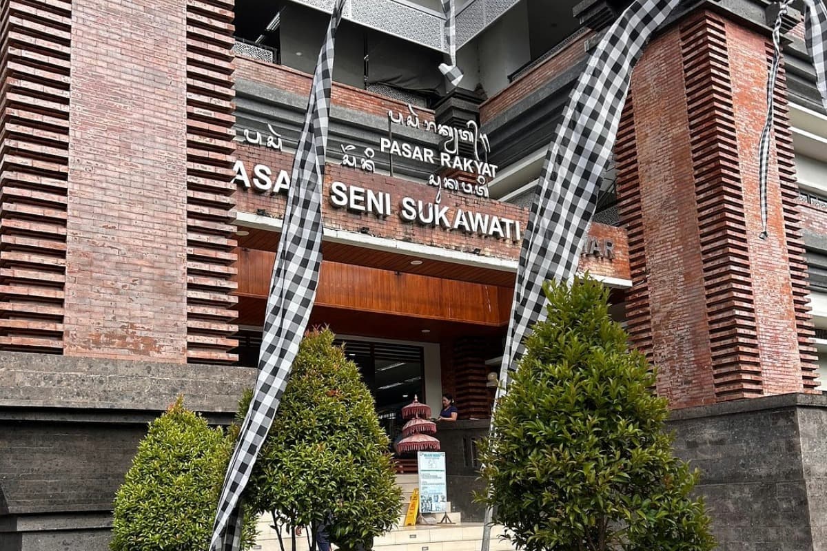 Entrance of Sukawati Art Market in Bali with brick building, signs, and traditional decorations outside.