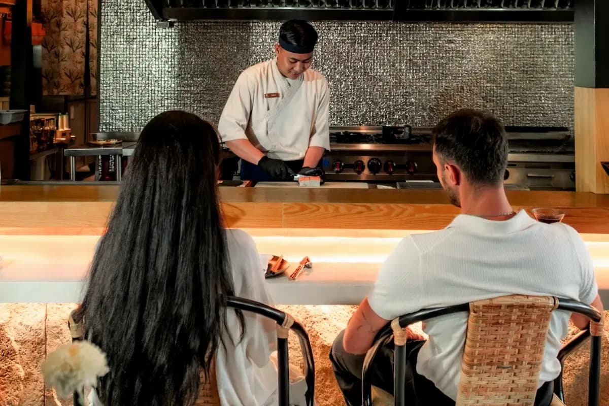 Chef prepares food at counter while guests watch, showing intimate chef’s table dining experience in Bali.