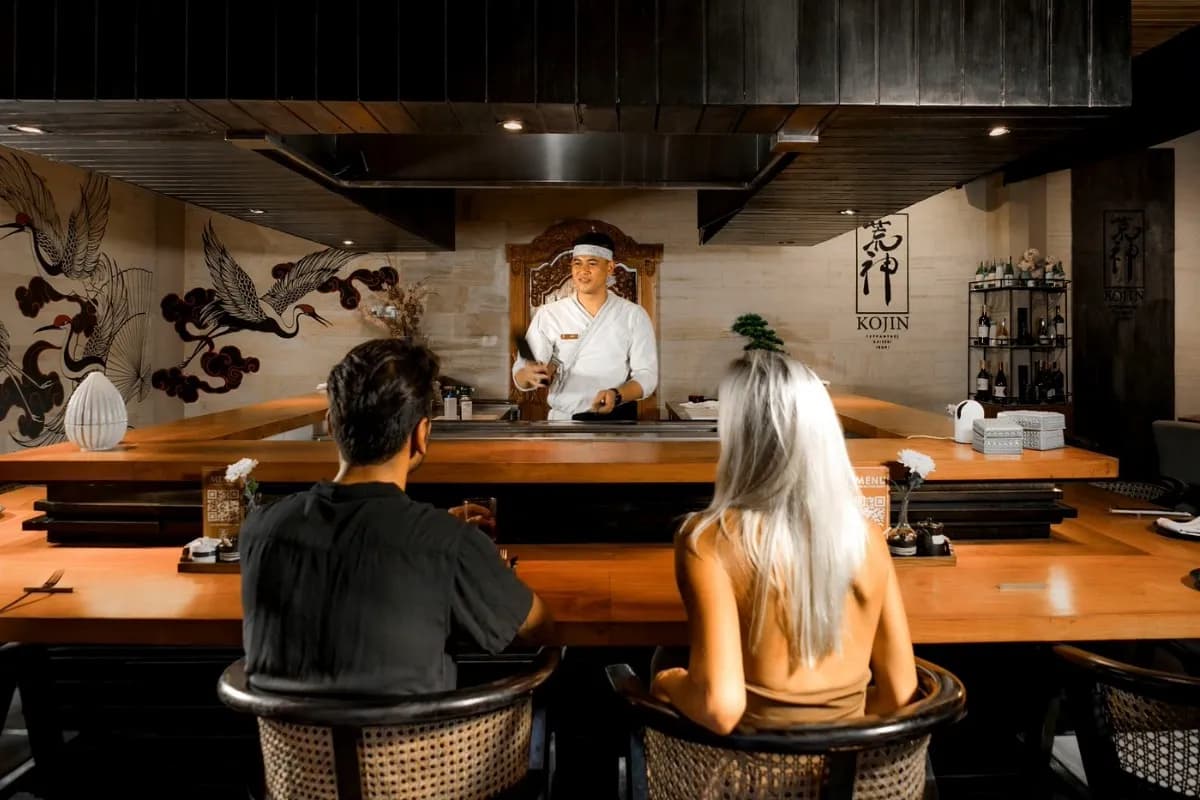 Chef prepares food at counter while guests watch, showing omakase dining experience in Bali.
