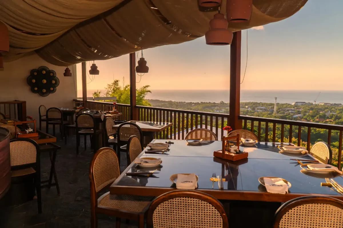 Open-air restaurant with tables facing ocean view at sunset, ideal for dining near Uluwatu Temple.