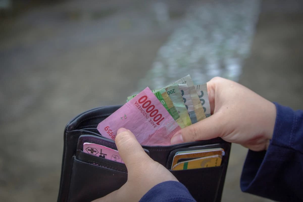 Tourist holding Indonesian rupiah in a wallet, showing currency preparation before visiting Bali.