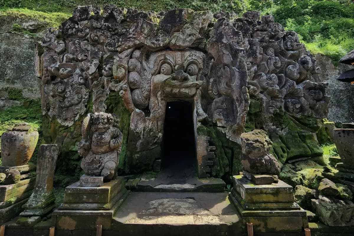 Stone entrance of Goa Gajah Temple with carved guardian face, a historic stop on a Bali cultural tour.