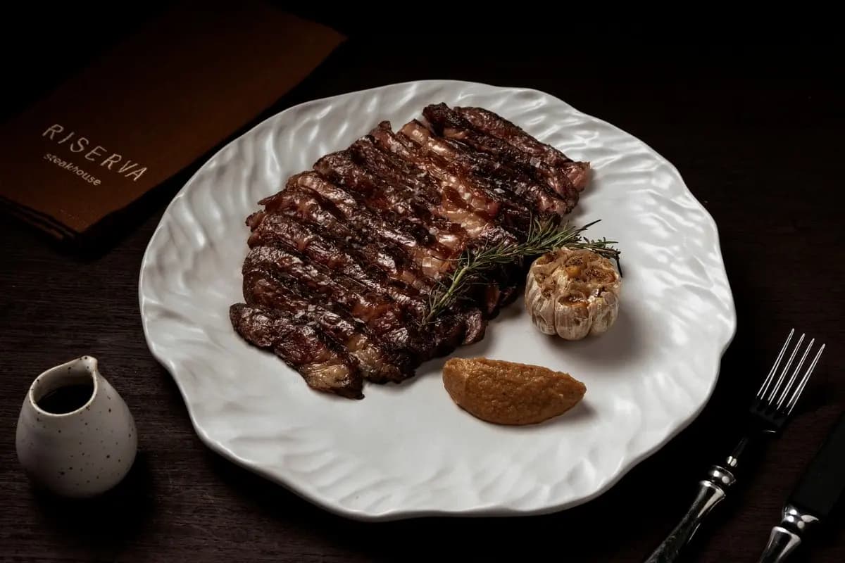 Grilled steak served with roasted garlic and sauce, highlighting a steakhouse dining experience in Ubud.